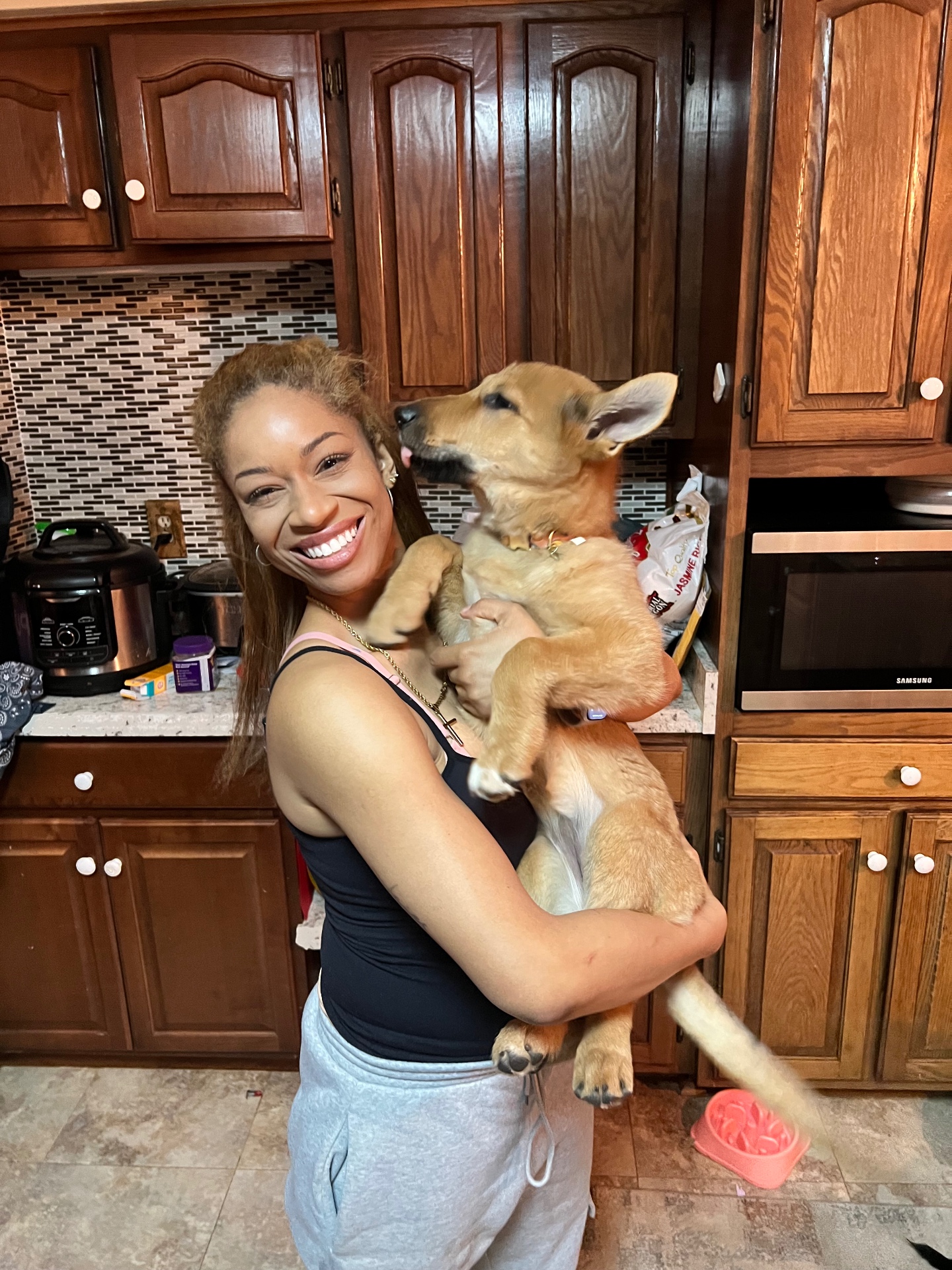 Victoria holding Eliza, her service dog, as a puppy in the kitchen.