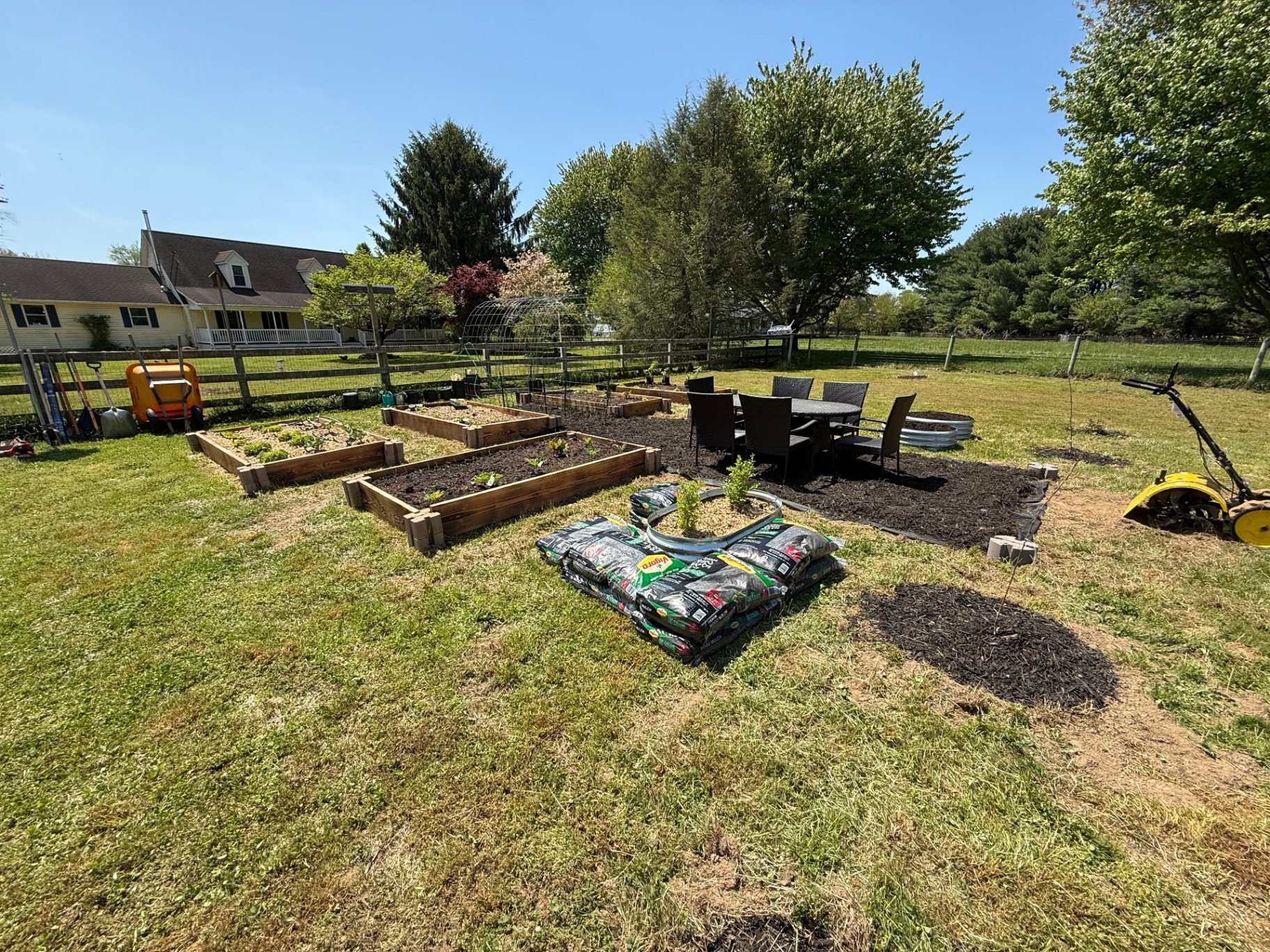 Raised garden beds being prepared beside the farmhouse.